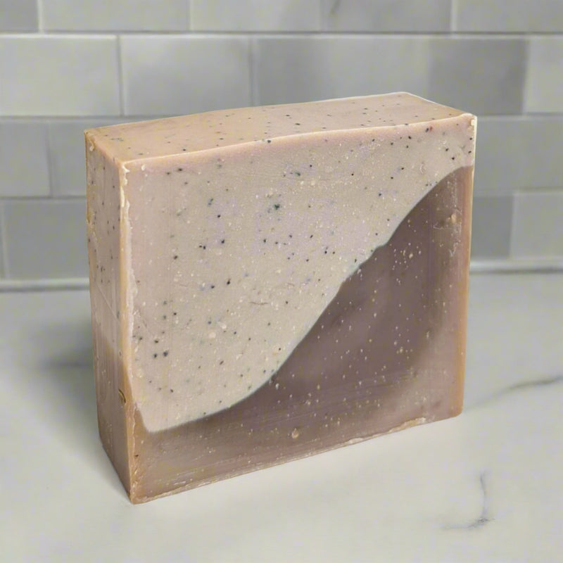 An exfoliating soap bar with the uplifting scent of coffee mixed with the sweet scent of vanilla and hazelnuts. Coffee grinds are used for exfoliation in one half of the soap bar, the other half hydrates and moisturizes with soy milk and shea butter.